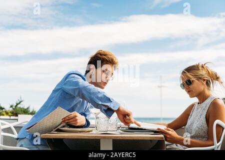 couple dans un restaurant, le gars lui dit ce qu'il faut manger en pointant vers le menu Banque D'Images