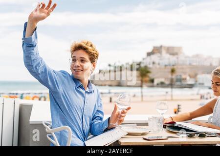 guy demande au serveur dans un restaurant extérieur pendant une date avec une jeune fille Banque D'Images