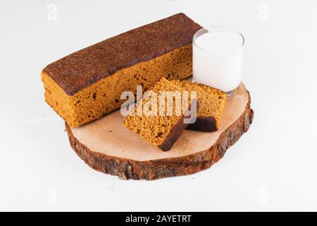 Gâteau traditionnel au pain d'épices avec miel, gingembre, cannelle, noix de muscade et anmis de Hollande avec un verre de lait sur fond blanc Banque D'Images