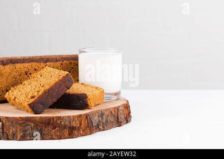 Gâteau traditionnel au pain d'épices avec miel, gingembre, cannelle, noix de muscade et anmis de Hollande avec un verre de lait sur fond blanc Banque D'Images