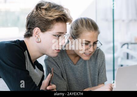 Stock photo d'une femme et d'un jeune homme qui sont concentrés regarder un écran d'ordinateur portable sur un bureau dans un espace de travail Banque D'Images