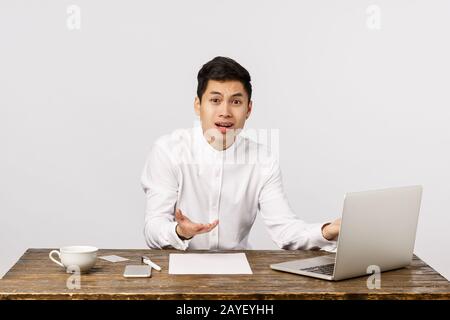 Frustré et contrarié, jeune responsable de bureau asiatique en difficulté, homme, assis et se répandre les mains sur les côtés, se plaignant, h Banque D'Images