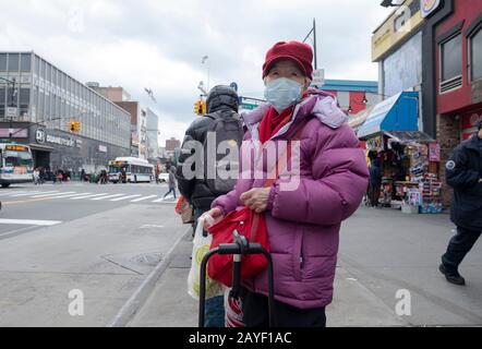 Une ancienne femme chinoise américaine à faire du shopping attend un bus sur Main Street dans Chinatown, Flushing, Queens, New York City. Banque D'Images