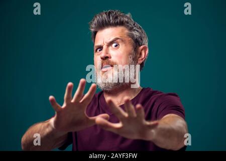 Un portrait d'un homme barbu effrayé dans un t-shirt rouge. Concept de personnes et d'émotions Banque D'Images