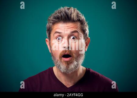 Un portrait de barbu surpris homme en t-shirt rouge. Concept de personnes et d'émotions Banque D'Images