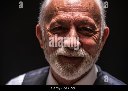 Portrait de l'homme senior souriant sur fond noir. Banque D'Images