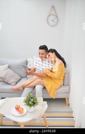 Jeune couple de détente à la maison de luxe avec les tablettes électroniques la lecture dans le salon sur le canapé-lit. Banque D'Images