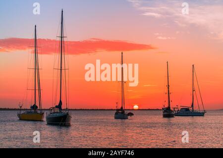 Groupe de bateaux à voile sur la mer au coucher du soleil Banque D'Images