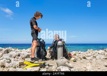 Deux plongeurs sur la plage préparent la plongée Banque D'Images