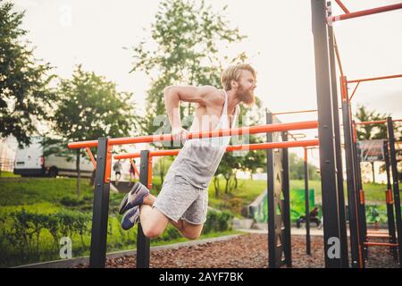 Monter les bras de l'entraînement sur les barres horizontales battes entraînement Triceps et biceps faire l'UPS. Bel homme faisant de l'exercice sur le para Banque D'Images
