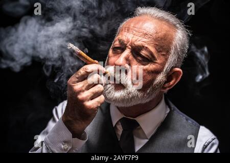 Portrait de l'homme senior sérieux qui sauve le cigare. Banque D'Images