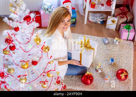 Jeune fille à l'arbre de Noël avec un cadeau dans ses mains Banque D'Images