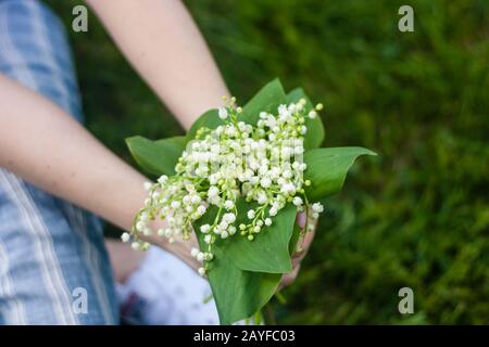 Femme tenant un joli bouquet de lilly de fleurs de vallée dans le temps chaud ensoleillé, fille avec fleurs Banque D'Images