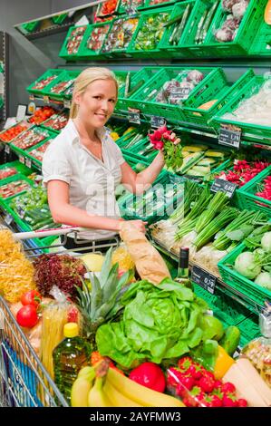 Eine junge Frau kauft Obst und Gituese auf einem Wochenmarkt. Ernaehrung und Ausführung von Grünen. Banque D'Images