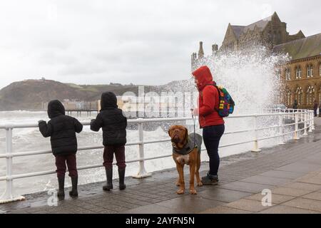 Aberystwyth, Ceredigion, Pays De Galles, Royaume-Uni. 15 février 2020 Royaume-Uni Météo: Une femme et deux enfants regardent les vagues, tandis que les défenses de la mer le long de la ville côtière d'Aberystwyth prennent une autre battue que Storm Dennis churns au-dessus de la mer, créant d'énormes vagues de crashing le long de la promenade. © Ian Jones/Alay Live News Banque D'Images