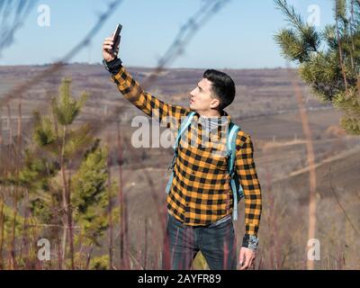 jeune homme dans des vêtements décontractés perdu dans la nature essayer de capter le signal sur le téléphone Banque D'Images