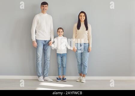 Bonne famille souriante tout en se tenant sur fond gris. Banque D'Images
