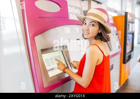 Jeune femme payant à la billetterie d'une station de métro ou de chemin de fer Banque D'Images