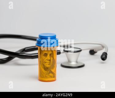 Prescription médicament médicament comprimé bouteille avec 100 dollars de facture et stéthoscope sur fond blanc. Concept de médicaments, de soins de santé et d'assurance médicale Banque D'Images