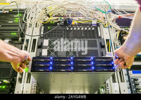 Installation d'un nouveau serveur de base de données moderne. Maintenance d'équipements informatiques dans le centre de données. Remplacement du serveur dans le rack de commutateurs Banque D'Images