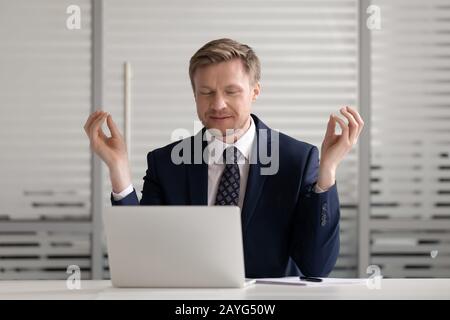 Homme d'affaires calme distrait du travail médiant sur le lieu de travail Banque D'Images