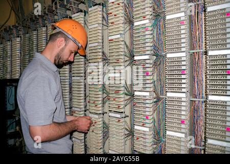Le technicien connecte les fils au panneau de raccordement de la salle du serveur du centre de données. L'ingénieur travaille avec l'équipement d'échange téléphonique. Banque D'Images