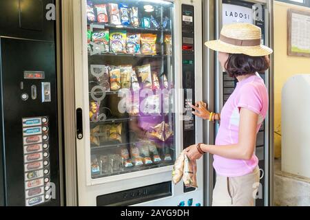 24 JUILLET 2018, RIBES DE FRESSER, ESPAGNE : femme achetant des chips et autres en-cas à partir d'un distributeur automatique Banque D'Images