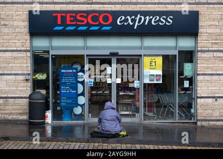 Le mendiant se cousue à la porte d'un magasin Tesco Express sur Holyrood Road, Édimbourg, Écosse, Royaume-Uni. Banque D'Images