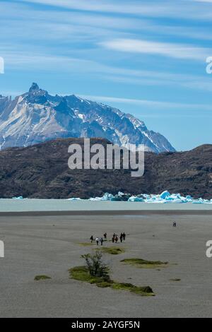 Touristes sur la plage de Lago Gray avec des icebergs flottants du glacier gris dans le parc national de Torres del Paine en Patagonie, au Chili. Banque D'Images