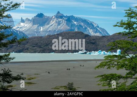 Touristes sur la plage de Lago Gray avec des icebergs flottants du glacier gris dans le parc national de Torres del Paine en Patagonie, au Chili. Banque D'Images