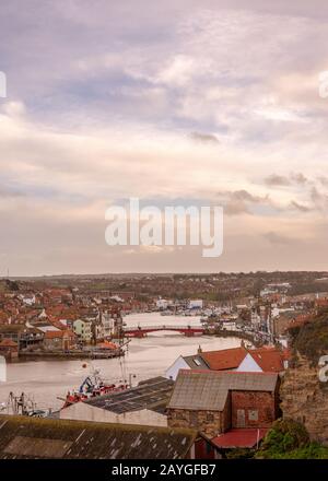 Port de Whitby et ville donnant vers l'intérieur. Les bâtiments de la ville se regroupent autour du port et un pont s'étend sur l'eau. Un ciel nuageux est au-dessus. Banque D'Images