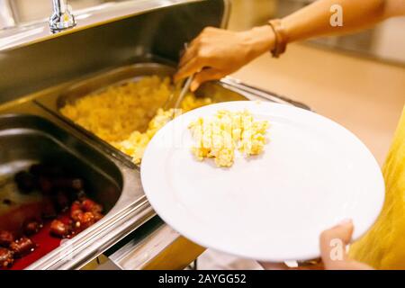 Femme choisissant et choisissant divers en-cas et plats sur une table au buffet du restaurant de l'hôtel. Tout ce que vous pouvez manger Banque D'Images