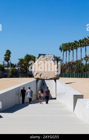 Les touristes se promenent sous la sculpture d'art public « Levitated Mass » de Michael Heizer, 2012. Resnick North Lawn à LACMA, Los Angeles, Californie, États-Unis Banque D'Images