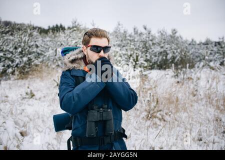 Tourisme en parka bleue soufflant à ses mains en gants pour les réchauffer Banque D'Images