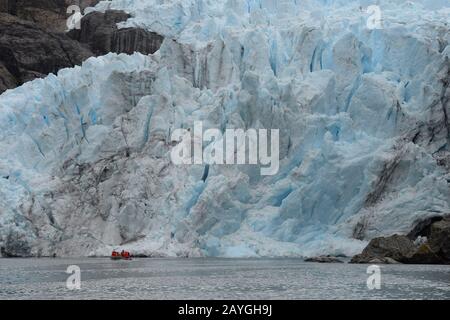 Un zodiaque avec les touristes navigue en face du glacier Condor dans le détroit d'Agostini, Cordillera Darwin, à Tierra del Fuego dans le sud du Chili. Banque D'Images