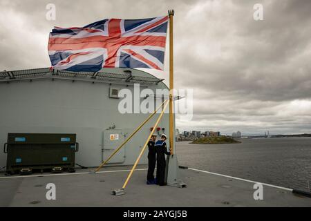 Les marins hissent l'Union Jack monter le personnel du nouveau porte-avions HMS QUEEN ELIZABETH de la Marine royale à l'arrivée à Halifax, en Nouvelle-Écosse. Banque D'Images