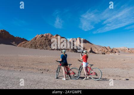 De jeunes femmes VTT à travers la vallée de la Lune près de San Pedro de Atacama dans le désert d'Atacama, dans le nord du Chili, prenant des photos de téléphone portable. Banque D'Images