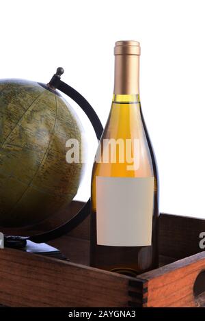 Gros plan d'une bouteille de vin blanc avec une étiquette vierge dans une caisse en bois avec globe ancien, sur blanc. Banque D'Images