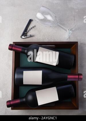 Flat Lay Wine Still Life : trois bouteilles de vin placées dans un plateau avec verre à vin et corkvec. Les flacons sont dotés d'étiquettes vierges. Banque D'Images