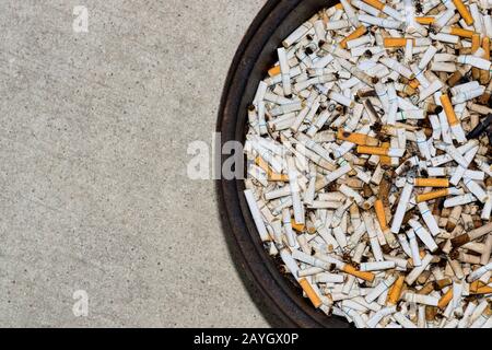 Mégots de cigarettes et de cigares jetés dans une station de tabac circulaire avec espace de copie sur la gauche. Dépendance à la nicotine et habitude de fumer sale. Banque D'Images