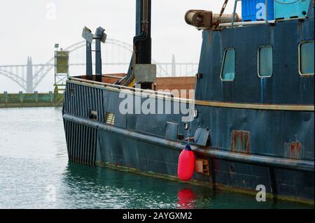 Un bateau noir se trouve à Marina avec une bouée rouge en suspension. Banque D'Images