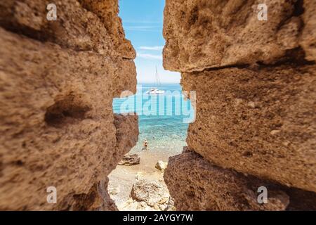 Vue sur la baie en Méditerranée avec le yacht et les plages à travers les rochers dans la vieille forteresse côtière ruinée Banque D'Images