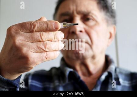 Homme âgé mesurant la température corporelle avec thermomètre au mercure. Concept de fièvre, traitement froid, symptômes du coronavirus Banque D'Images