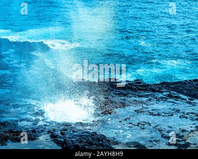 Trous de lave à Hawaï. L'océan érode la clayette de lave sous l'eau, puis souffle à travers des trous dans le haut. Banque D'Images