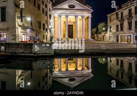 Venise la nuit, Italie. Panorama d'une rue déserte le soir. Ancienne église éclairée avec réflexion dans un canal d'eau. Promenade romantique toute la nuit Banque D'Images