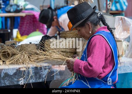 Une femme est en tissage des paniers sur le marché indigène de Saquisili dans les hautes terres de l'Équateur près de Quito. Banque D'Images