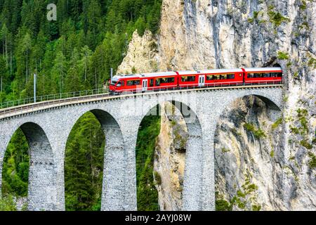 Landwasser Viaduc À Filisur, Suisse. C'est un monument célèbre des Alpes suisses. Le train express rouge part du tunnel de montagne sur le pont supérieur. Pittoresque Banque D'Images