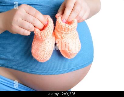 Femme enceinte tenant une belle chaussures de bébé en laine isolée sur blanc Banque D'Images