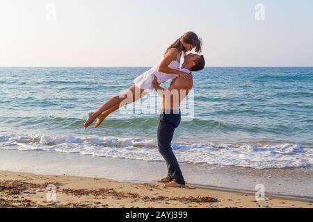 Après-midi d'été sur une plage de sable avec l'océan en arrière-plan, un jeune couple pratique une scène de danse. Banque D'Images