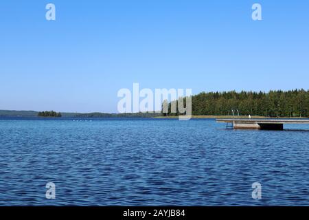 Quai de baignade en bois avec échelle en métal sur lac bleu calme journée ensoleillée sur la nature Finlande station naturelle idyllique Banque D'Images